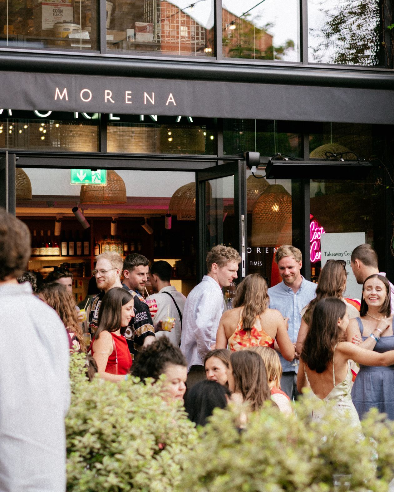 People gathered outside a restaurant named 'Morena'